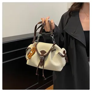 Detail of canvas bucket bag with brown leather trim and retro wooden bead charm