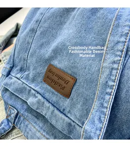 Detail of blue denim crossbody bag with brown leather patch and white stitching texture
