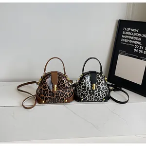 Detailed view of leopard print shell bags with gold metallic buckle and sturdy handles