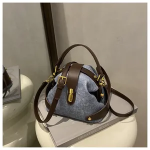 Λεπτομέρεια τσάντας denim με καφέ δερμάτινες λαβές και χρυσό μεταλλικό κλείδωμα