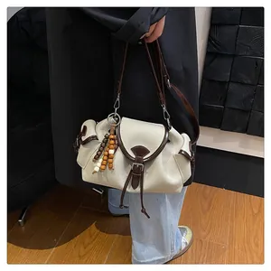 Detail of beige canvas bucket bag with brown leather trim and ethnic wood bead charm