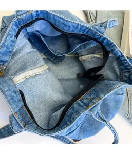 Detail of the black zipper closure and inner compartment of the light blue denim tote bag