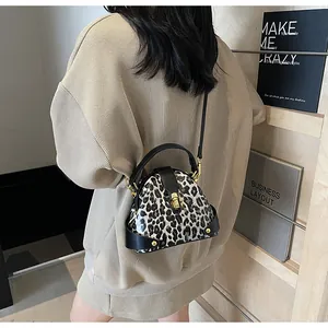 Close-up of leopard print shell bag featuring golden metal clasp and black leather edges