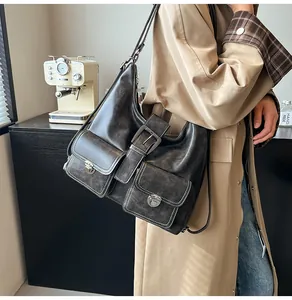 Detail of dark grey distressed leather tote bag with functional front buckled pockets