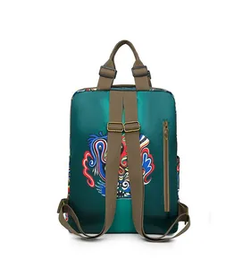 Detail of green nylon backpack featuring a colorful dragon embroidery and bronze buckles