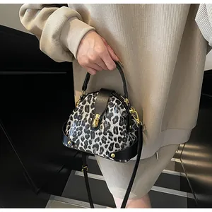 Detail of leopard print shell bag with gold twist lock and metal rivet studs