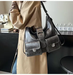 Detail of distressed grey leather hobo bag with vintage pockets and silver buckles