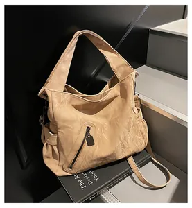 Λεπτομέρεια της μπεζ τσάντας tote με φαρδύ λουράκι και τσέπες με μεταλλικό φερμουάρ