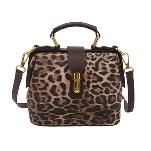 Leopard print crossbody bag with brown leather handles and golden hardware in retro style