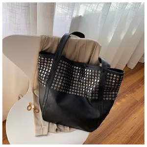 Close-up of black rivet tote bag with silver studs on a stylish modern chair