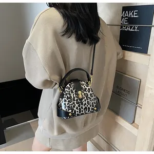 Street style shot of a leopard print shell bag with gold twist lock and black strap