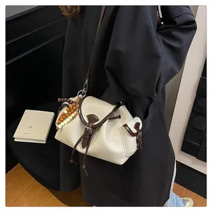 Detail of a beige bucket bag featuring a drawstring closure and wooden bead charm