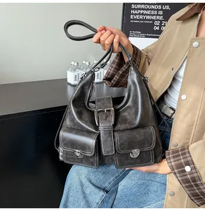 Detail of distressed grey leather shoulder bag featuring industrial metal buckles and dual front pockets