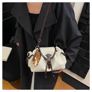Detail of canvas and brown leather bucket bag with wooden bead charm and drawstring pocket