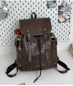 Detailansicht brauner Vintage-Rucksack mit Schnallenriemen und süßem Bärenanhänger