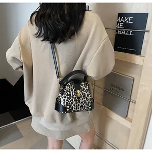 Close-up of leopard print shell bag with golden vintage lock and black leather handle