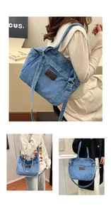 Detailed view of blue denim tote bag with leather logo patch and adjustable straps