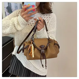 Close-up of a retro brown bucket bag featuring a beaded charm and leather straps