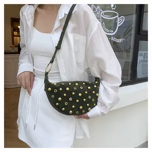 Detail of dark green suede half-moon bag with gold studs and adjustable shoulder strap