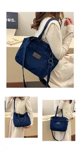 Detail of dark blue denim tote bag with leather logo tag and adjustable silver buckles