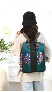 Detail of the green satin backpack featuring traditional colorful totem embroidery patterns