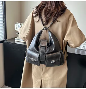 Model wearing dark grey vintage faux leather backpack with metallic turn-lock detail