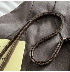 Detail of coffee leather strap with white stitching and silver buckle on a blazer