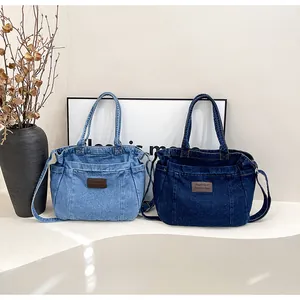 Detail of blue denim tote bags with leather brand tags and adjustable shoulder straps