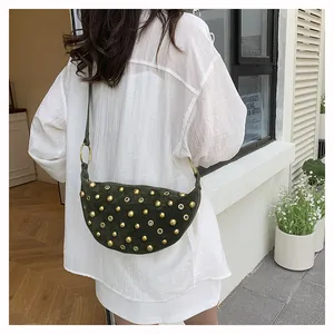 Detail of olive green crescent bag with gold rivets and eyelets on suede texture