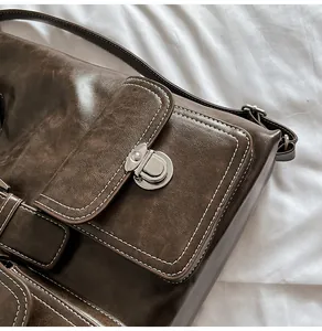 Detail of vintage brown leather bag with white contrast stitching and silver metal buckle