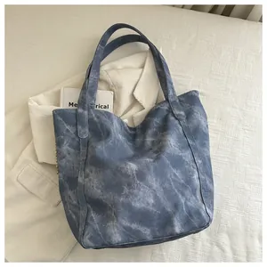 Λεπτομέρεια της μπλε tie-dye τσάντας tote με μεταλλικά καρφιά πάνω σε μαλακά κλινοσκεπάσματα