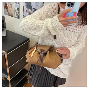Detail view of brown canvas bucket bag with wood bead decor and crossbody strap