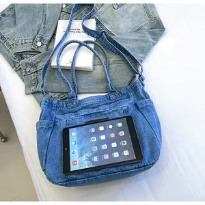 Blue denim tote bag with side pockets and adjustable strap shown with a tablet