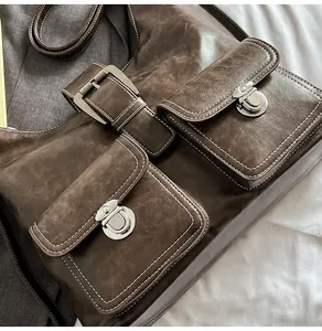 Close-up of vintage brown tote bag featuring silver metal buckles and oiled leather texture