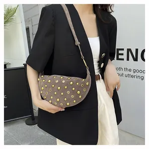 Detail of grey suede crescent bag with gold metal studs shown on shoulder