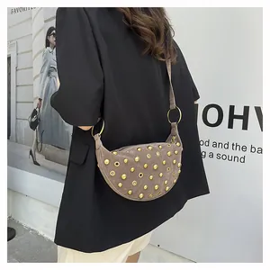Detail of mocha suede crescent bag featuring golden rivets and metallic eyelet decor
