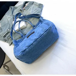 Detailed close-up of blue washed denim tote bag with brown label and adjustable straps
