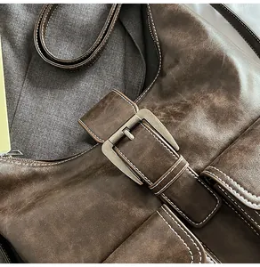 Macro shot of dark brown vintage leather bag with large buckle and contrast stitching