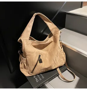 Λεπτομέρεια ανοιχτόχρωμης καφέ τσάντας με πτυχωτή υφή δέρματος και φαρδύ λουράκι
