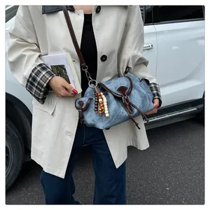 Dettaglio della borsa a secchiello blu con ciondolo in legno e patta in pelle marrone