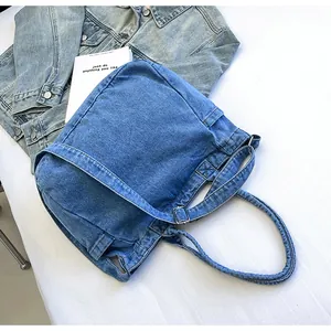Detailed flat lay of a blue denim tote bag with adjustable strap and metal buckle