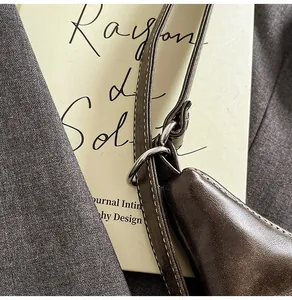 Close-up of dark brown leather bag with white contrast stitching and silver metal D-ring