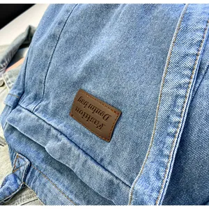 Detail of blue denim fabric with brown leather patch featuring Fashion Denim bag text