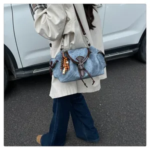Detail of vintage canvas bucket bag featuring leather trim and boho beaded charms