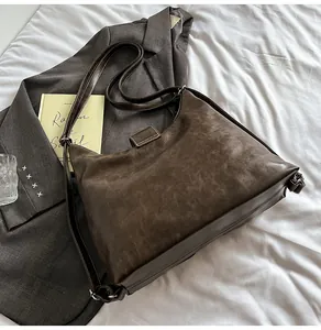 Detail of dark brown vintage leather tote with adjustable strap and contrast white stitching