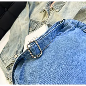 Detailed close-up of blue denim tote bag featuring adjustable silver metal hardware buckle