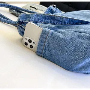Detailed close-up of a blue denim tote bag's outer pocket with a smartphone inside
