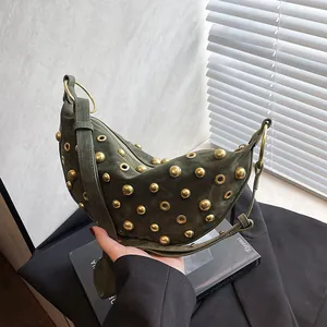 Olive green crescent shoulder bag with golden punk studs and grommets in a lifestyle setting