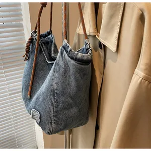 Detail of blue denim tote bag featuring rustic rope handles and frayed fabric patch accents
