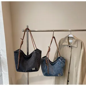 Detail of vintage denim tote bags with knotted rope straps and washed fabric texture